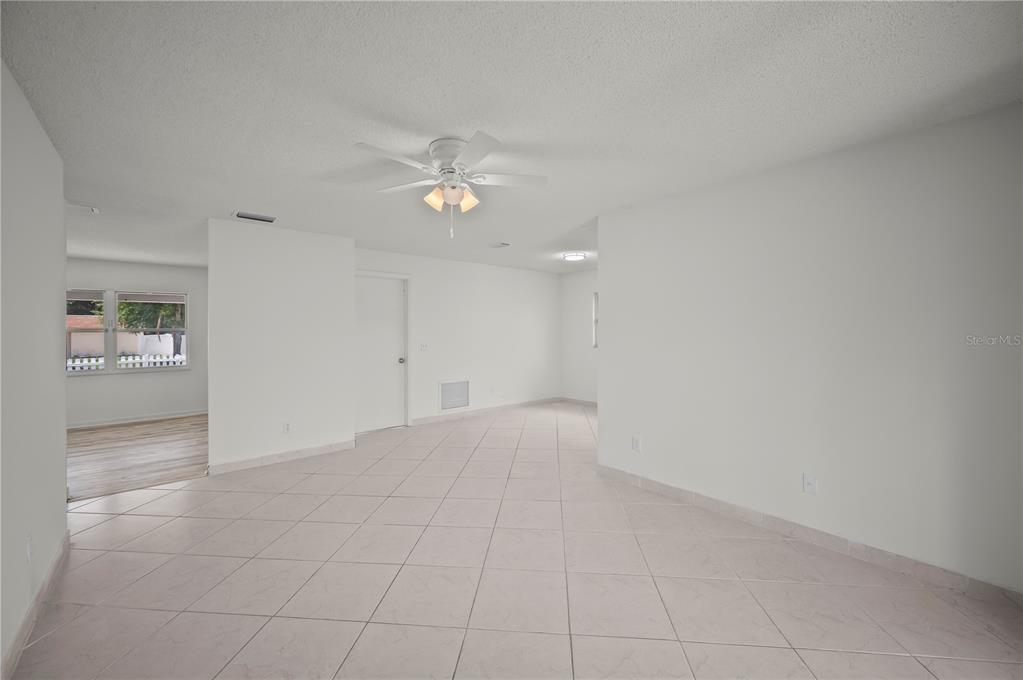 An open-concept room features white walls, a ceiling fan, and light-colored tile flooring — 405 N HAWTHORN CIRCLE, WINTER SPRINGS, FL