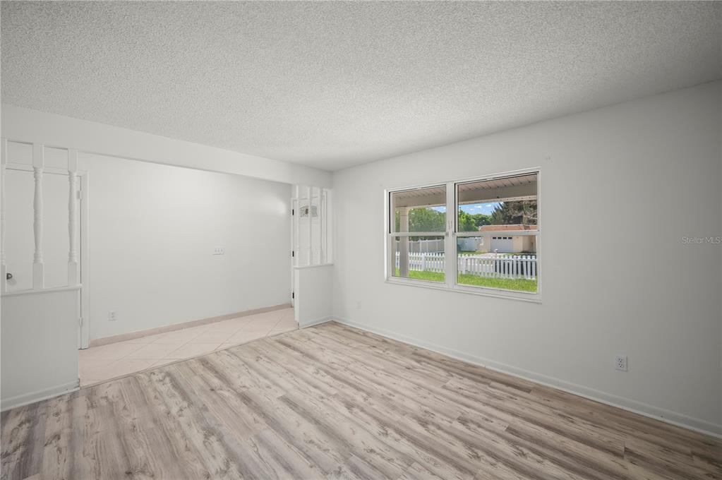 A living room with light wood-look flooring, white walls, and a window overlooking a yard — 405 N HAWTHORN CIRCLE, WINTER SPRINGS, FL
