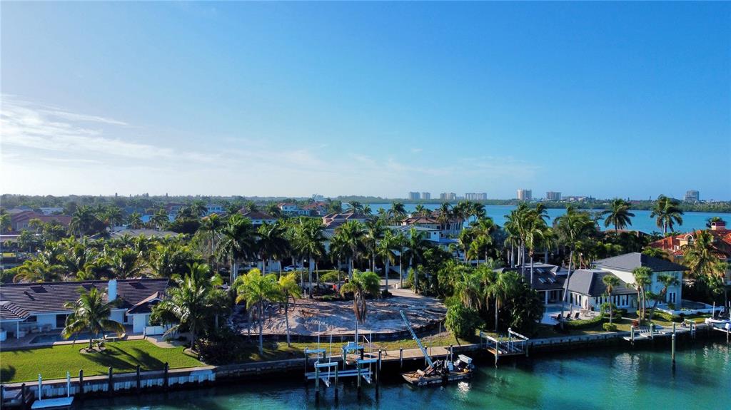 An aerial view of a waterfront property featuring a cleared lot, palm trees, and boat docks — 109 N WARBLER LANE, SARASOTA, FL