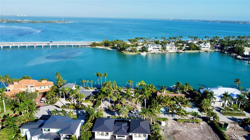 An aerial view shows waterfront homes, palm trees, and a bridge over a blue bay — 109 N WARBLER LANE, SARASOTA, FL