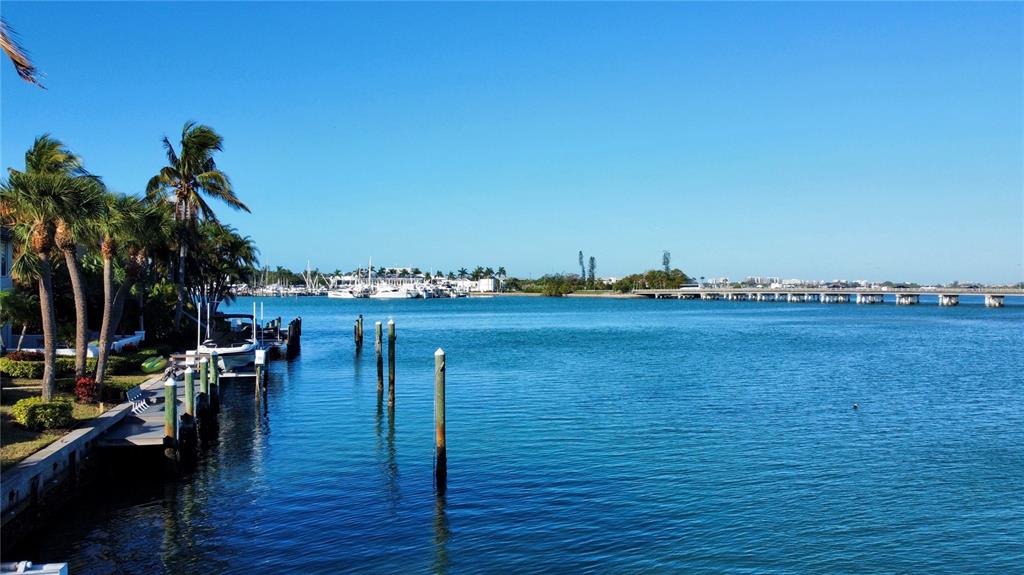 A view of a waterfront canal with a boat dock, palm trees, and a bridge — 109 N WARBLER LANE, SARASOTA, FL