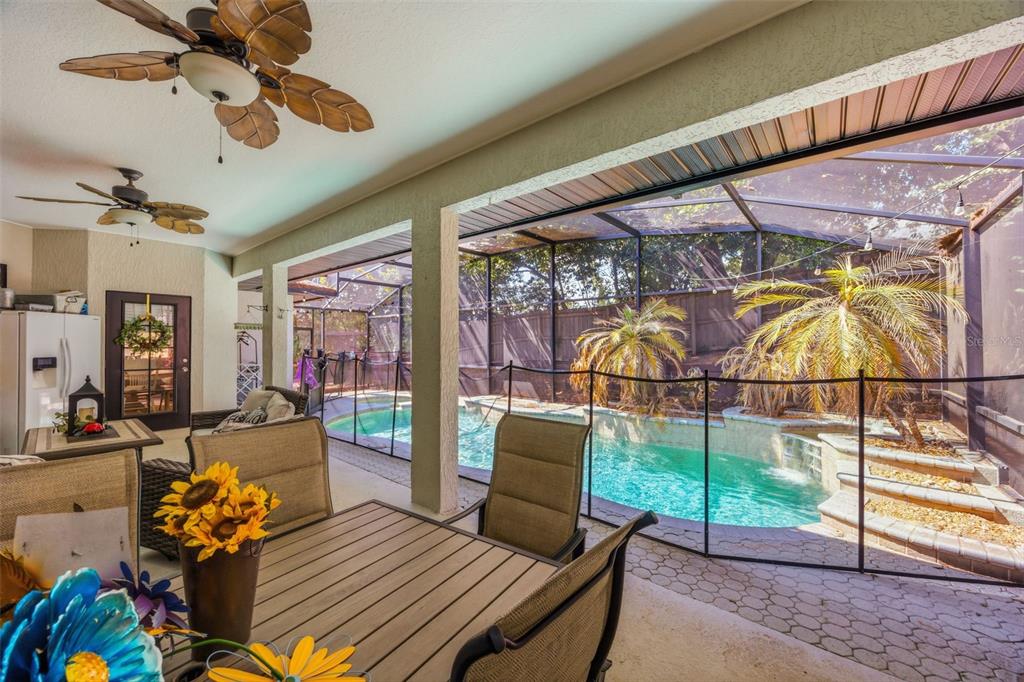 A covered patio features a dining set, ceiling fans, and a screened-in pool area — 13031 SUNSHINE VIEW COURT, CLERMONT, FL