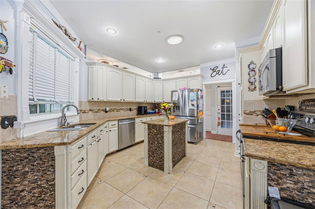 A kitchen with white cabinets, granite countertops, stainless steel appliances, and a tiled floor — 13031 SUNSHINE VIEW COURT, CLERMONT, FL