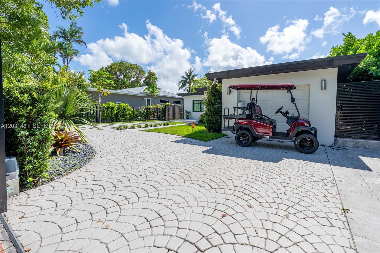 A red golf cart is parked on a patterned paver driveway in front of a house — 7850 Hawthorne Ave, Miami Beach FL 33141, MIAMI BEACH, FL