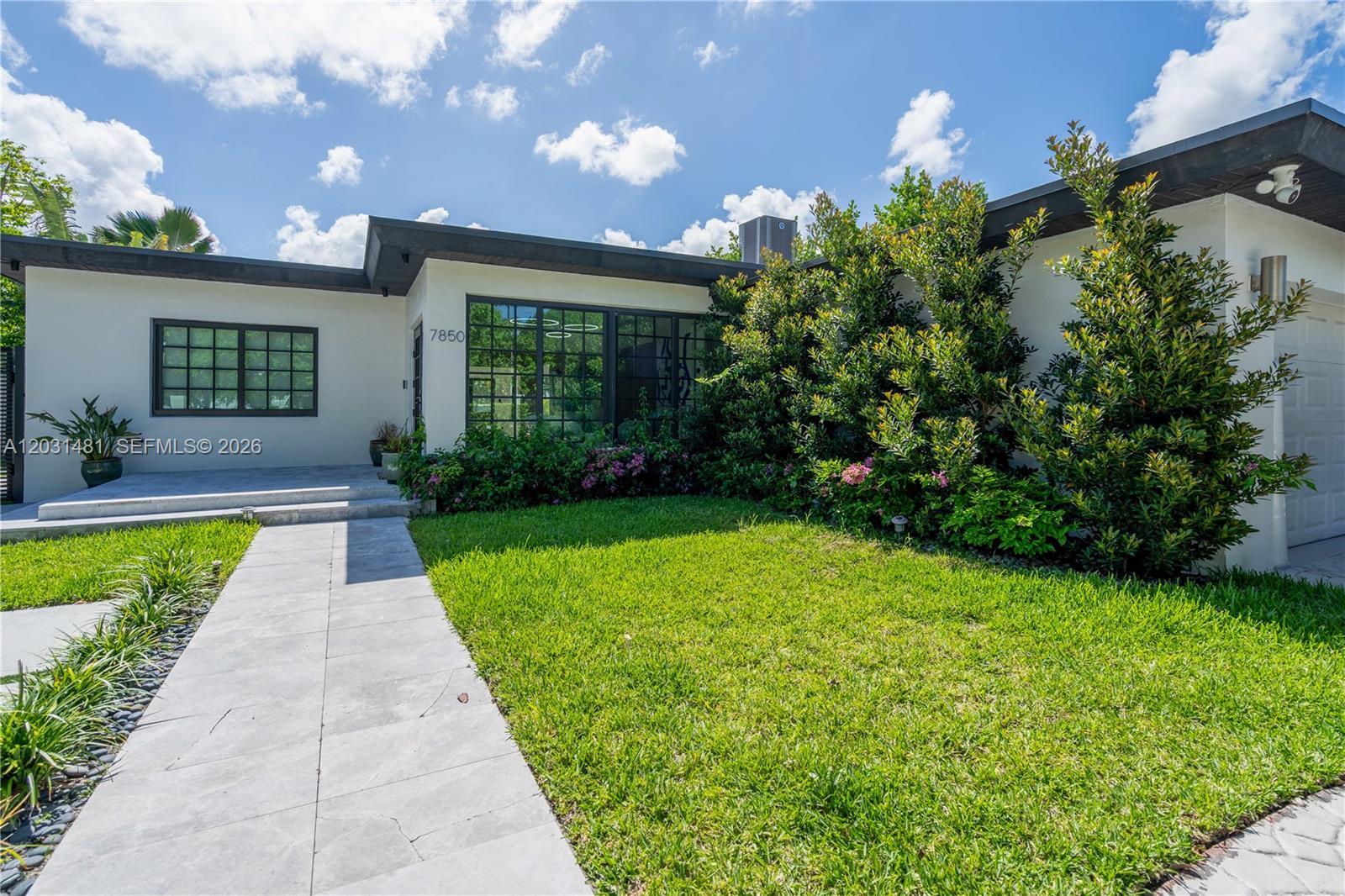 A single-story house features a white exterior, large grid windows, and a stone walkway — 7850 Hawthorne Ave, Miami Beach FL 33141, MIAMI BEACH, FL