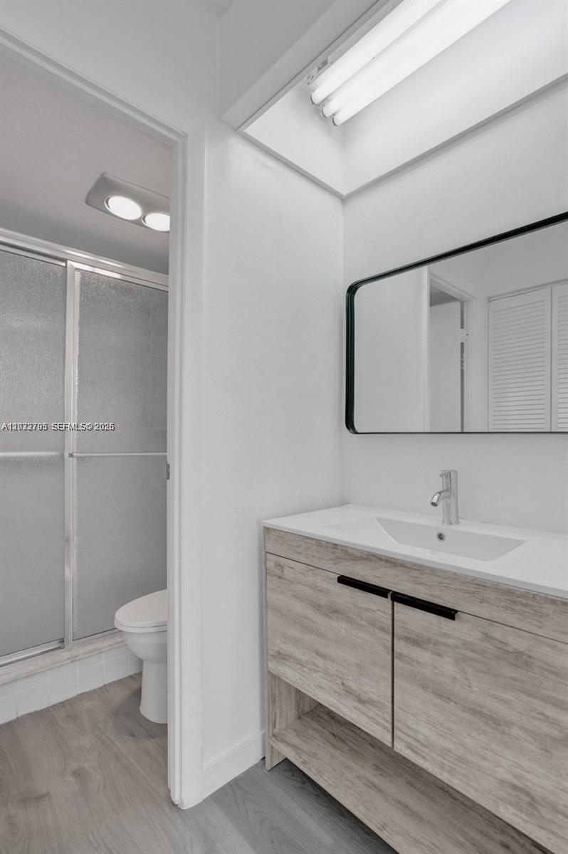 A bathroom features a wood-look vanity, a rectangular mirror, and a glass-enclosed shower — 3821 Environ Blvd # 403, Lauderhill FL 33319, LAUDERHILL, FL