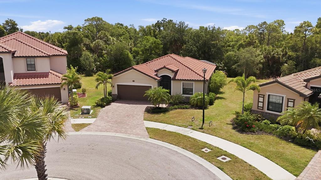 An aerial view shows a single-story house with a tile roof and paved driveway — 20930 VALORE COURT, VENICE, FL