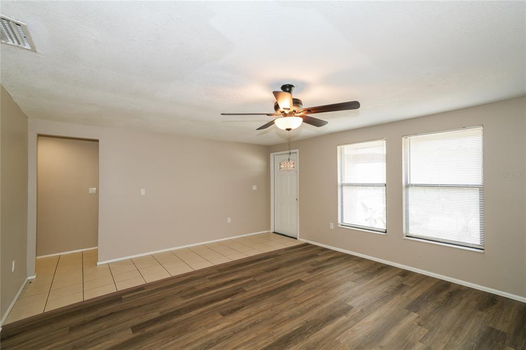 An empty living room features wood-look flooring, a ceiling fan, and light-colored walls — 2836 CINNAMON BEAR TRAIL, PALM HARBOR, FL