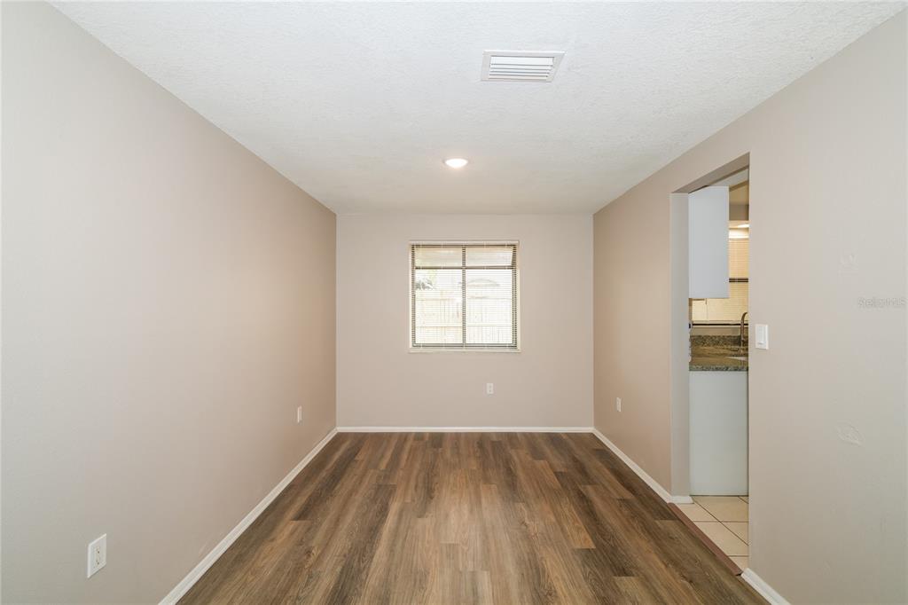 A living room features wood-look flooring, a tiled entryway, a ceiling fan, and two windows — 2836 CINNAMON BEAR TRAIL, PALM HARBOR, FL