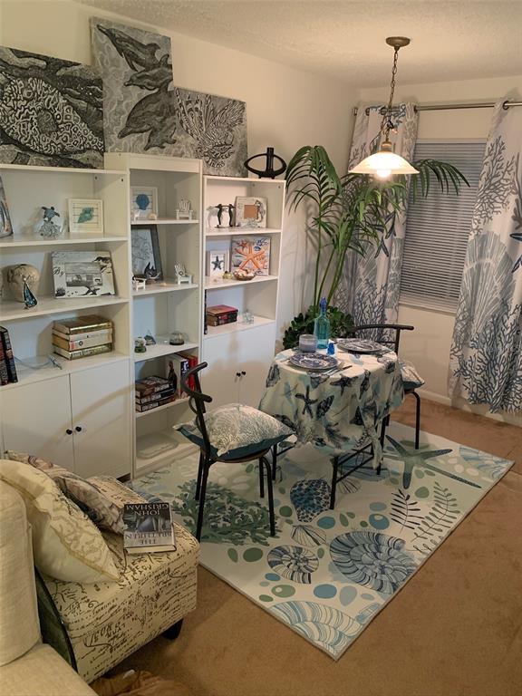 A dining area features a small round table, bookshelves, and coastal-themed decor on a rug — 10004 CORTEZ ROAD W UNIT 102, BRADENTON, FL