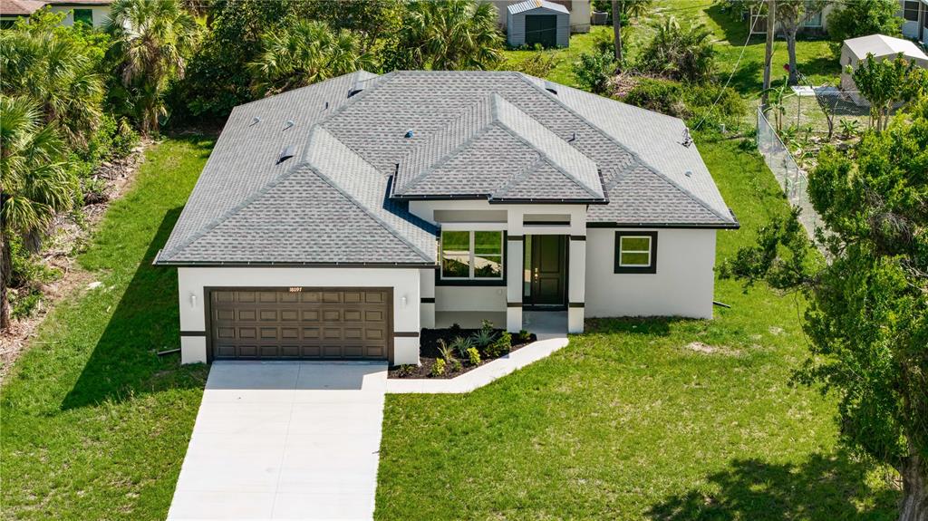 An aerial view of a single-story house with a gray roof and a concrete driveway — 18097 COCHRAN BOULEVARD, PORT CHARLOTTE, FL