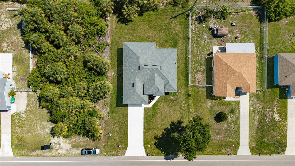 An aerial view shows a single-story house with a gray roof and a concrete driveway — 18097 COCHRAN BOULEVARD, PORT CHARLOTTE, FL
