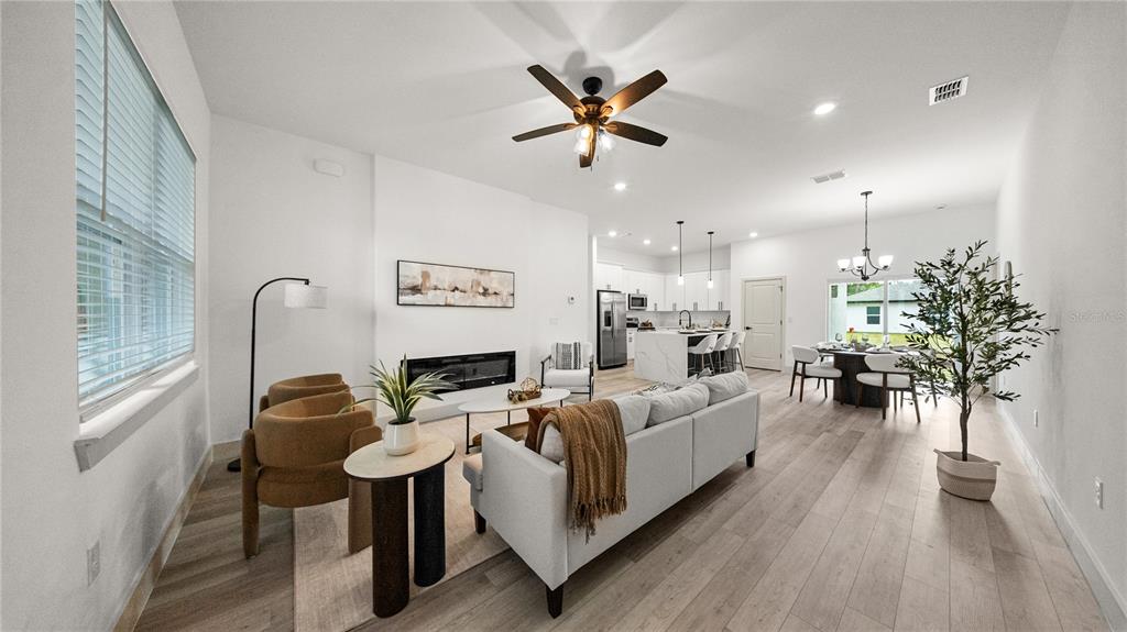 An open-concept living room and kitchen area with light wood flooring and a fireplace — 18097 COCHRAN BOULEVARD, PORT CHARLOTTE, FL