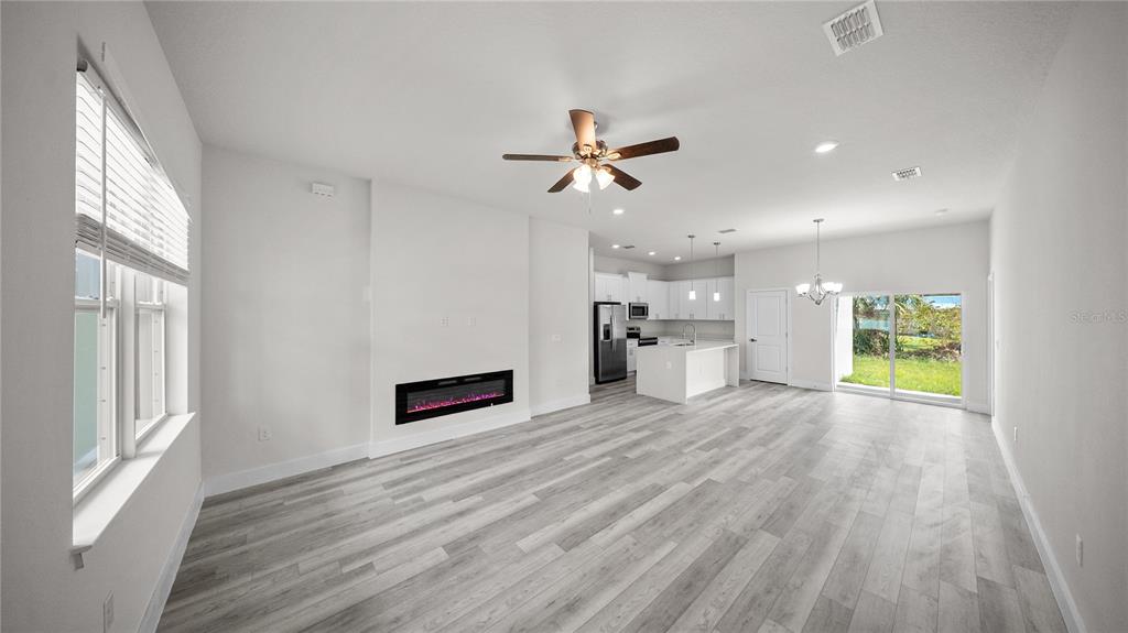 An open-concept living room and kitchen featuring a linear fireplace and light wood flooring — 18097 COCHRAN BOULEVARD, PORT CHARLOTTE, FL