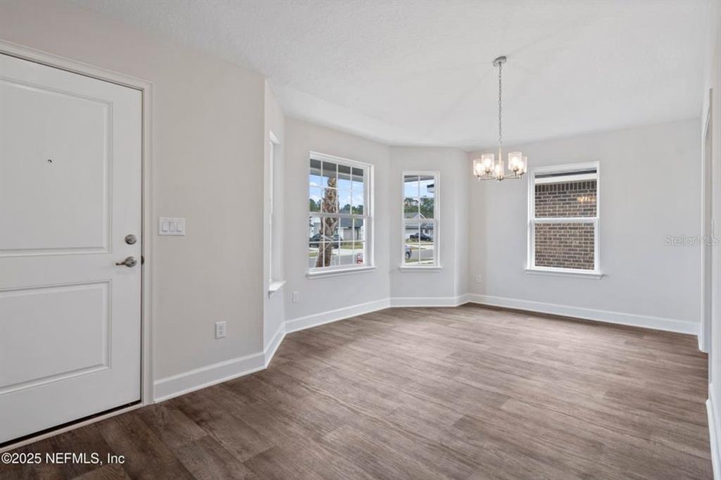 An empty dining room features light gray walls, wood-look flooring, and a bay window — 129 PRITCHARD DRIVE, PALM COAST, FL