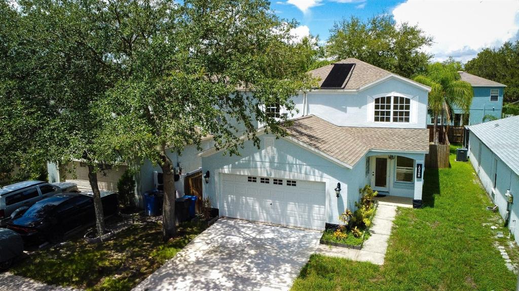 An aerial view of a two-story light blue house with a garage and solar panels — 10468 BLACKMORE DRIVE, TAMPA, FL