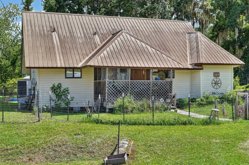 A one-story house with a metal roof, light siding, and a lattice-enclosed front porch — 110 W PALM AVENUE, CRESCENT CITY, FL