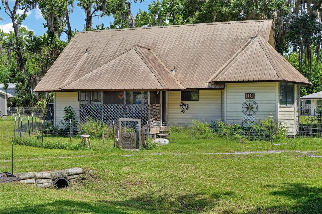 A one-story house with a metal roof, screened porch, and a fenced yard — 110 W PALM AVENUE, CRESCENT CITY, FL