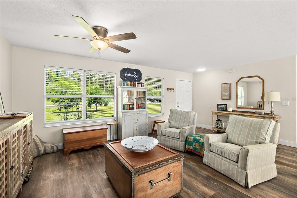A living room features wood-look flooring, two striped armchairs, a wooden coffee table, and a ceiling fan — 1893 WATER OAK ROAD, BUNNELL, FL
