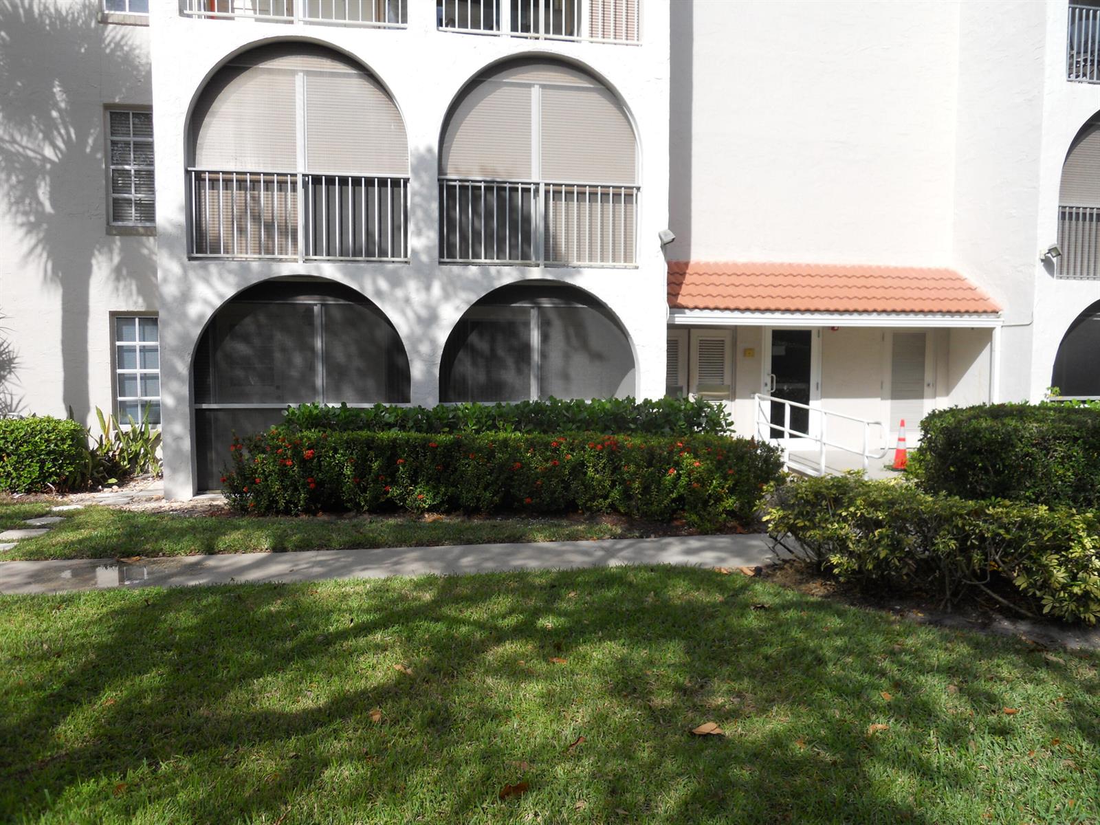 A multi-story building exterior features arched balconies, a tiled entryway, and landscaped shrubbery — 250 NE 20th Street # 123s, Boca Raton FL 33431, BOCA RATON, FL
