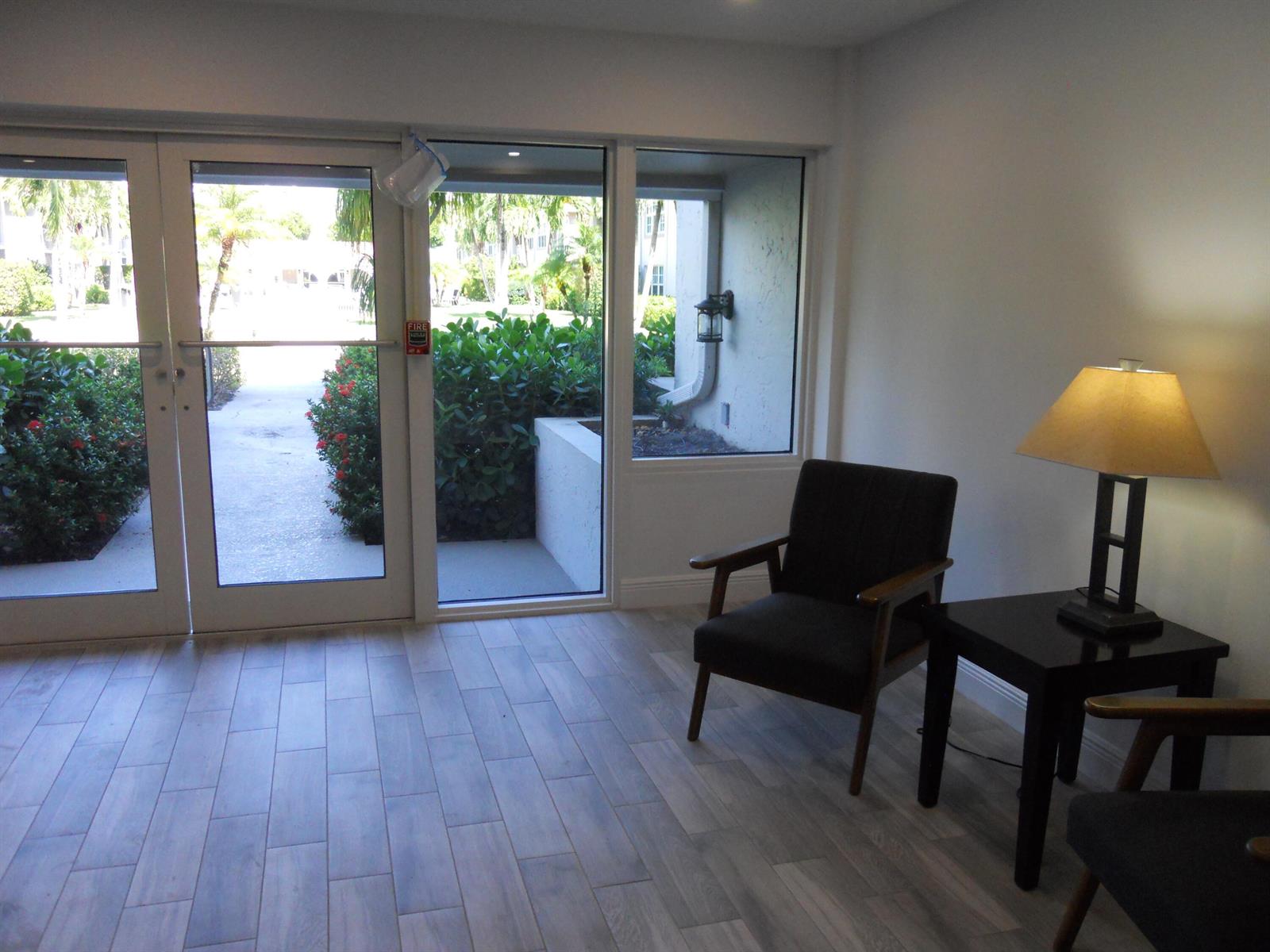 A waiting area features wood-look tile floors, two dark chairs, a side table, and glass doors — 250 NE 20th Street # 123s, Boca Raton FL 33431, BOCA RATON, FL