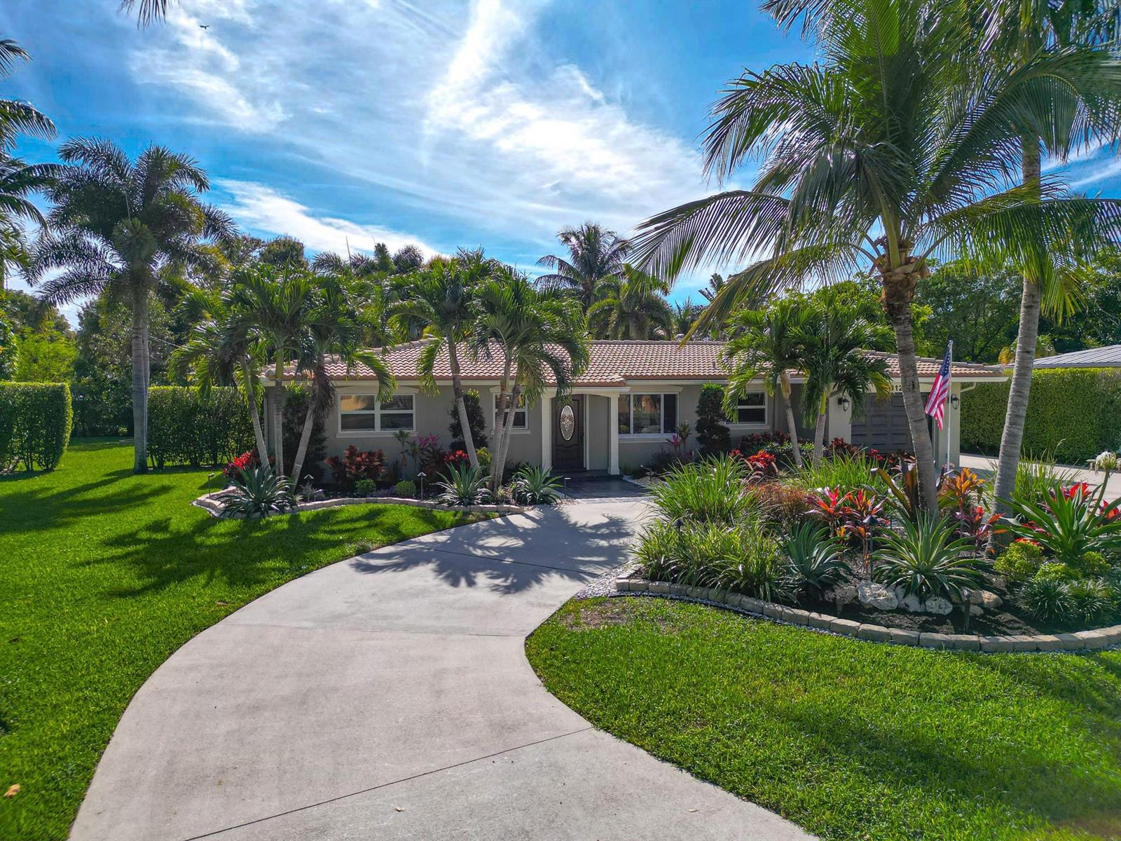 A single-story house with a curved driveway, palm trees, and landscaped gardens under a blue sky — 112 SW 24th Avenue, Boynton Beach FL 33435, BOYNTON BEACH, FL