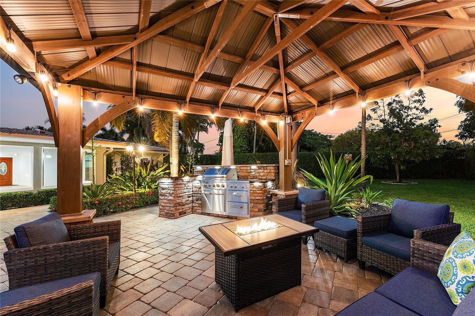 An outdoor patio features a covered kitchen area, a fire pit, and wicker seating — 112 SW 24th Avenue, Boynton Beach FL 33435, BOYNTON BEACH, FL