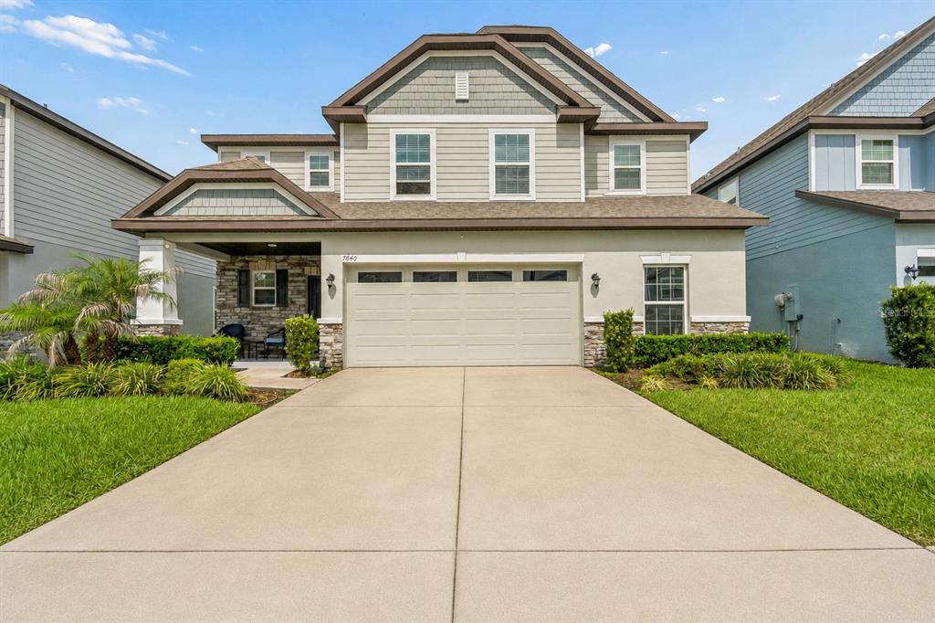 A two-story suburban house with a beige facade, stone accents, and a two-car garage — 7840 ABBY BROOKS CIRCLE, WESLEY CHAPEL, FL