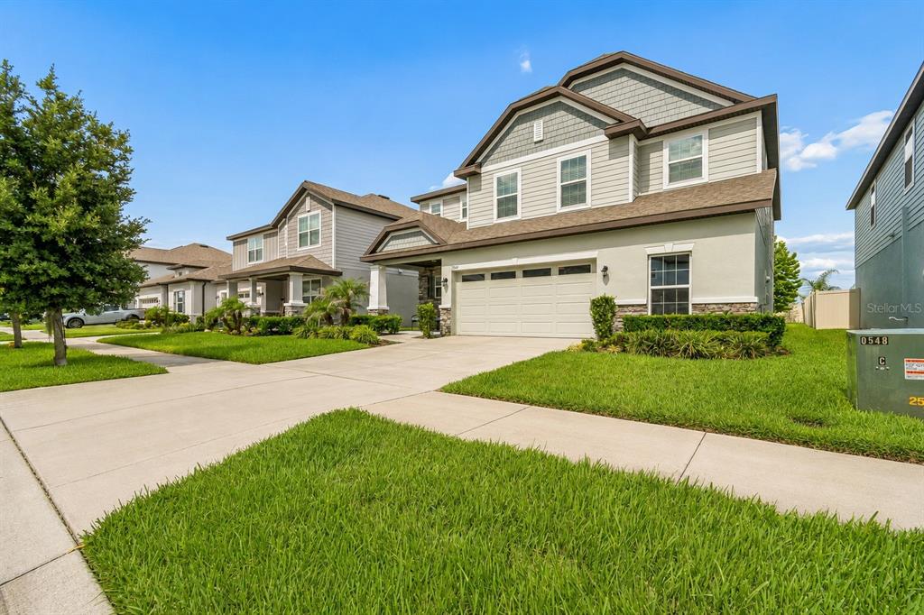 A two-story suburban house with a beige stucco and siding exterior and a concrete driveway — 7840 ABBY BROOKS CIRCLE, WESLEY CHAPEL, FL