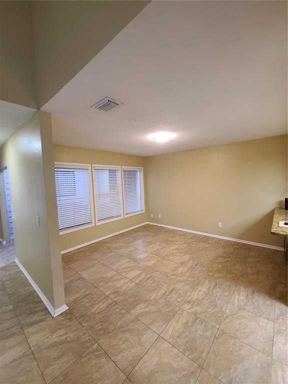 An empty room with tan walls, tiled flooring, and three windows with white blinds — 13701 LAZY OAK DRIVE, TAMPA, FL