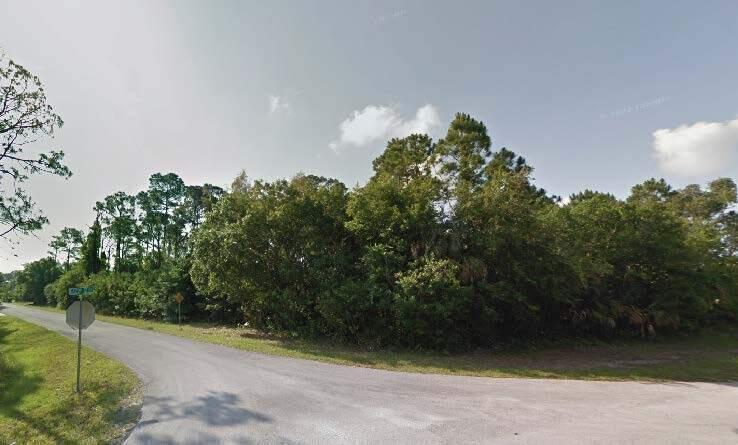 A paved road curves past a dense, wooded lot with a stop sign in the foreground — 8702 Fort Pierce Boulevard, Fort Pierce FL 34951, FORT PIERCE, FL