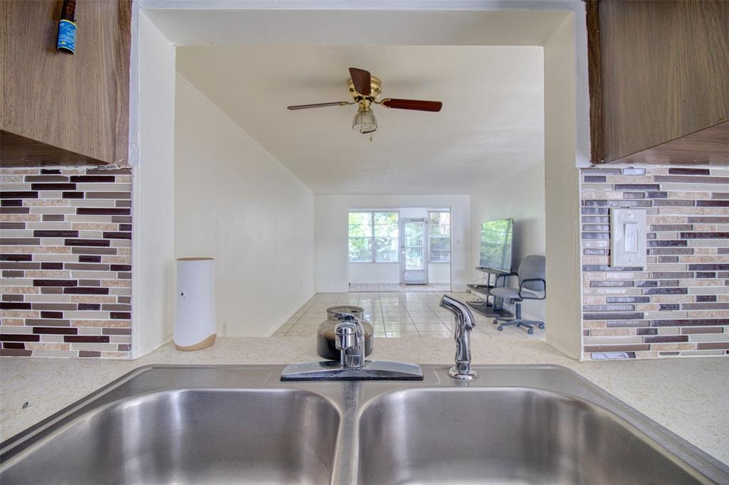 A view from a kitchen sink looking through a pass-through window into a living area — 4242 REDCLIFF PLACE UNIT C, NEW PORT RICHEY, FL