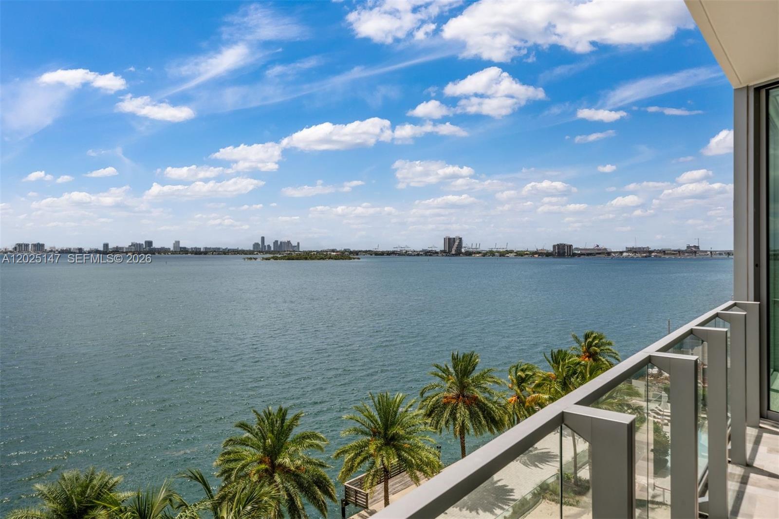 A balcony overlooks a large body of water with palm trees and a distant city skyline — 2900 NE 7th Ave # 504, Miami FL 33137, MIAMI, FL