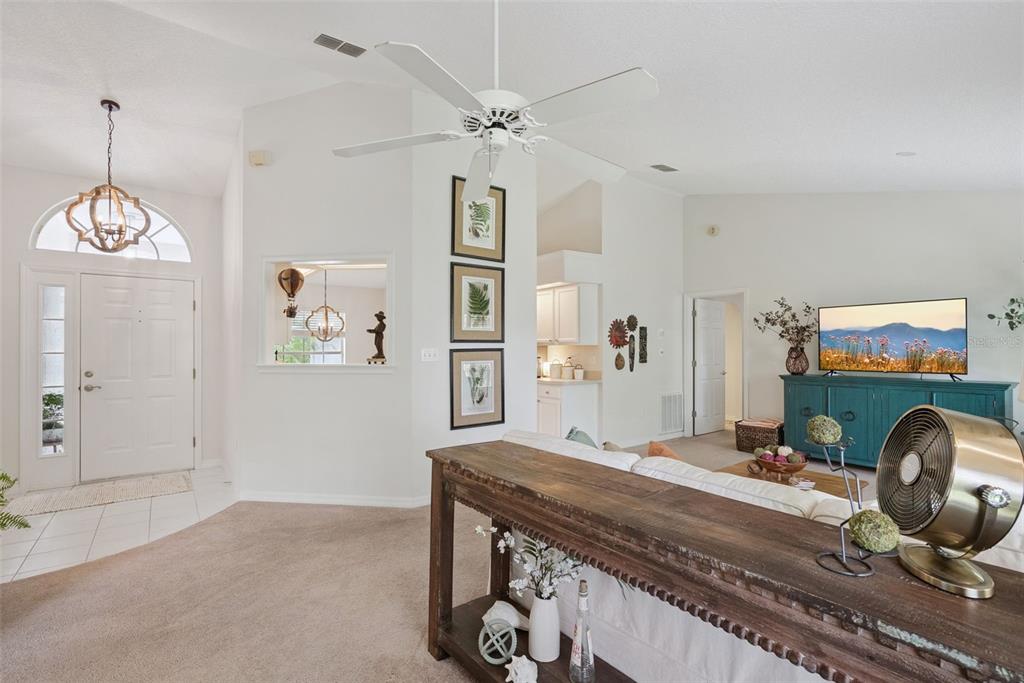 A living room features a ceiling fan, a console table, and a view into the kitchen — 613 HURON PLACE, MOUNT DORA, FL