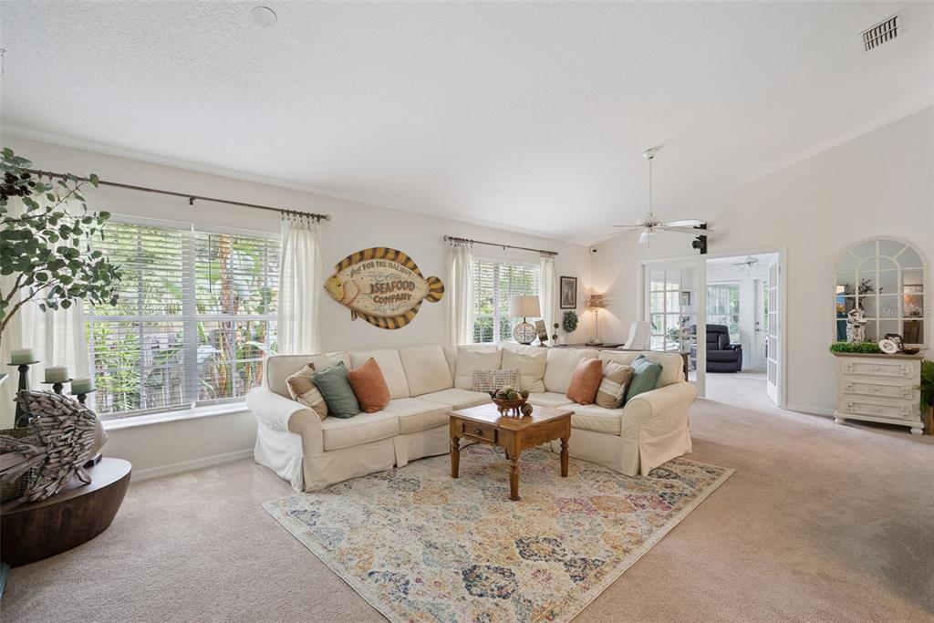 A living room features a white sectional sofa, a patterned area rug, and coastal decor — 613 HURON PLACE, MOUNT DORA, FL