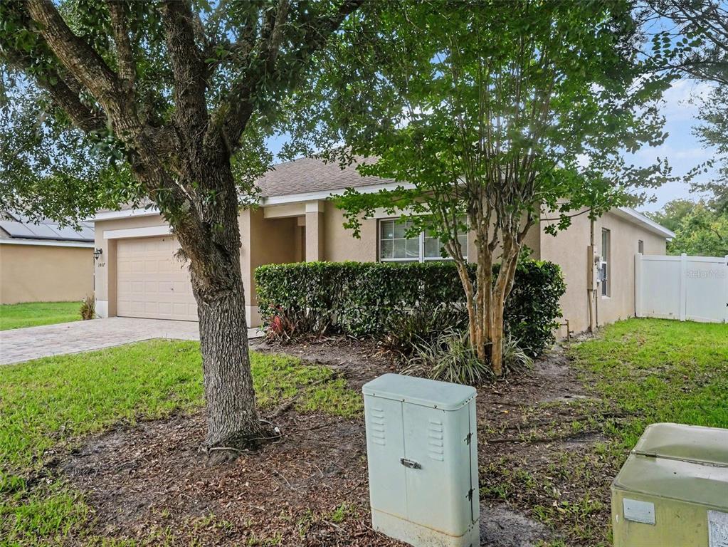 A beige single-story house with a two-car garage, a front lawn, and utility boxes — 1407 MARSH MEADOW LN, DAVENPORT, FL