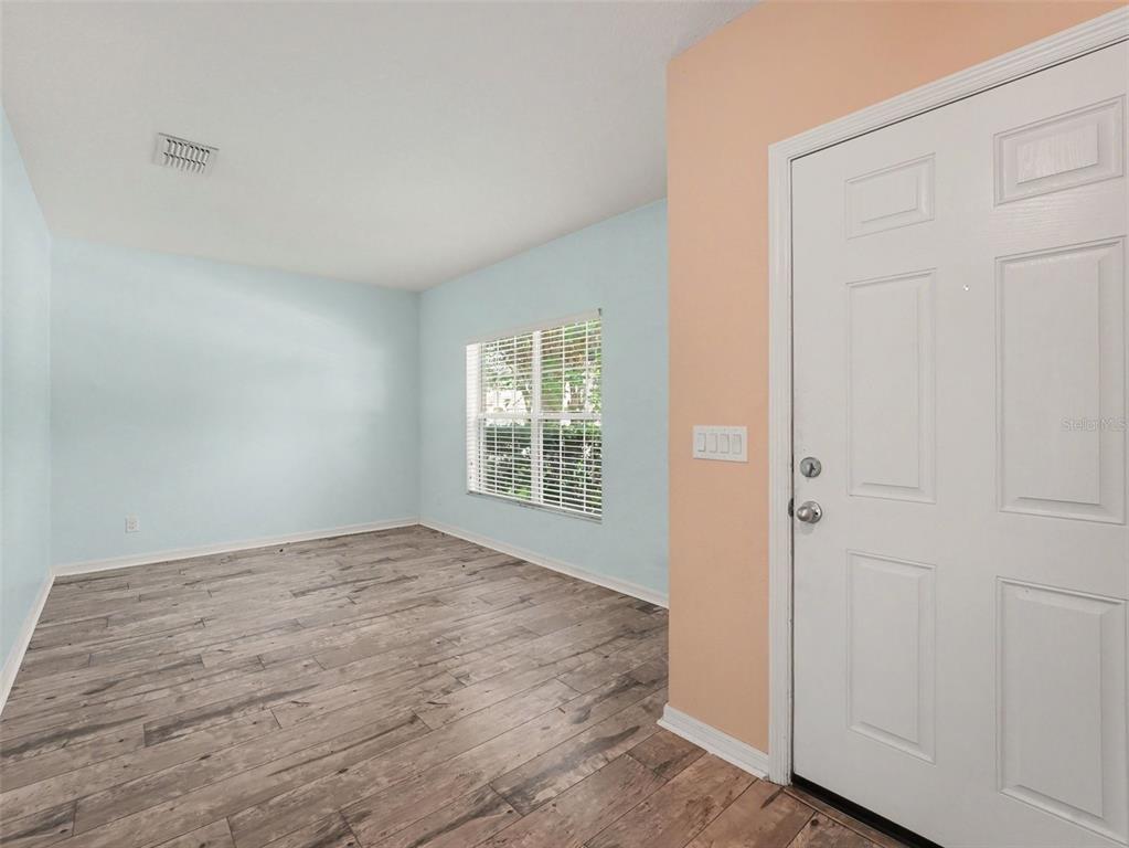 A room with light blue walls, wood-look flooring, a window, and a white entry door — 1407 MARSH MEADOW LN, DAVENPORT, FL