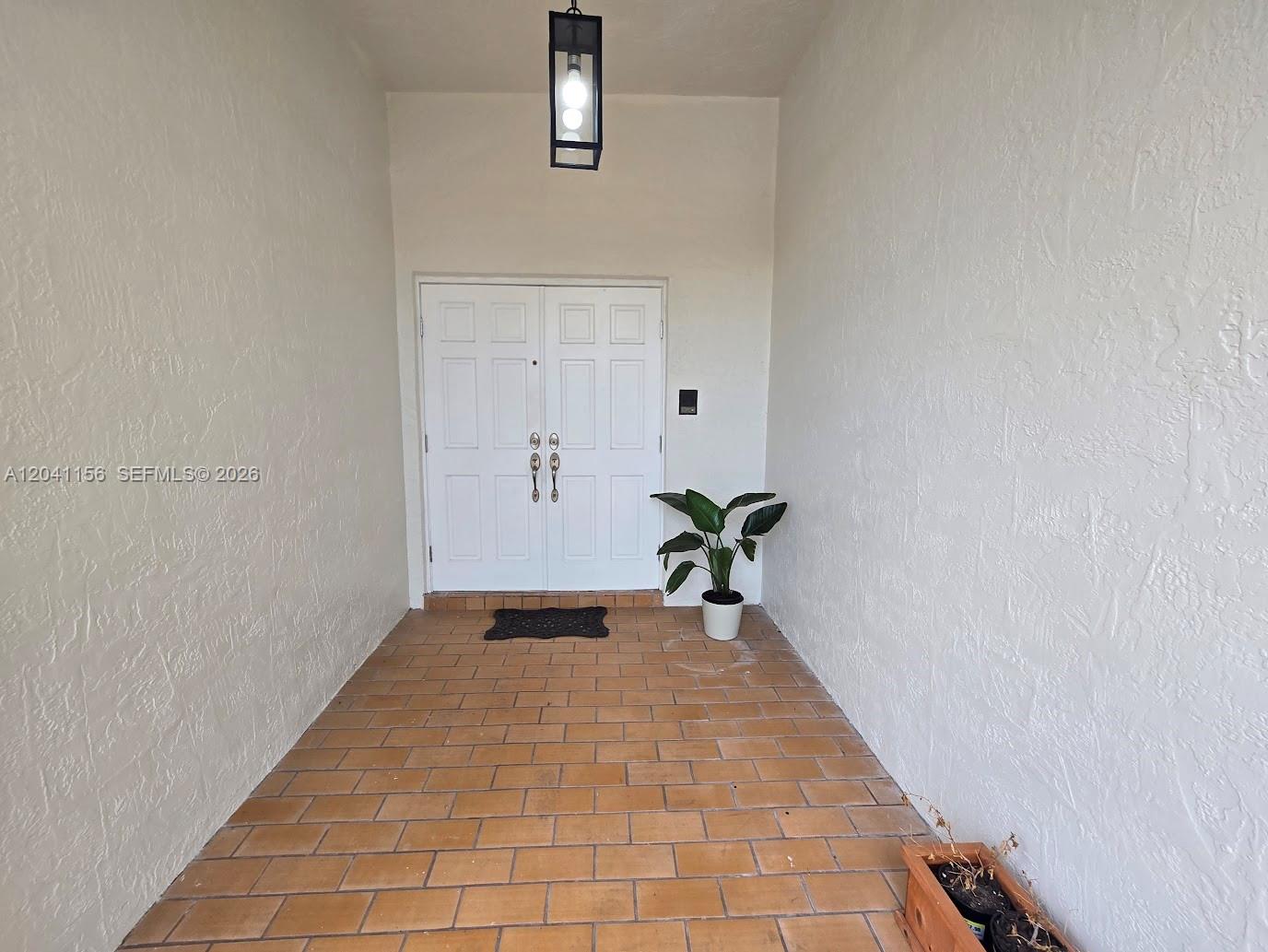 A covered entryway features a brick floor, white walls, and a double front door — 15630 SW 46th Ter, Miami FL 33185, MIAMI, FL