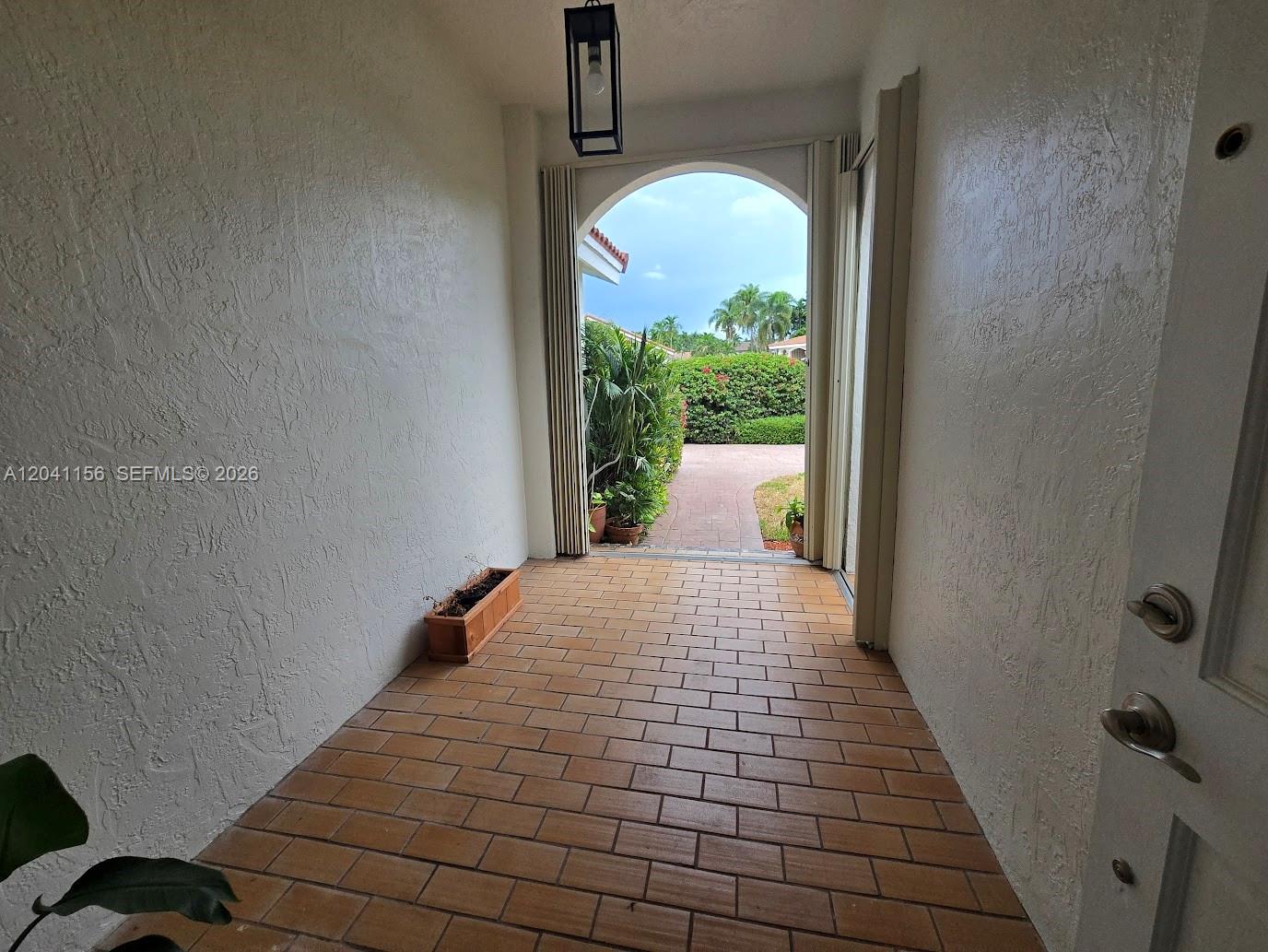 A tiled entryway leads through an arched doorway to an outdoor walkway and garden — 15630 SW 46th Ter, Miami FL 33185, MIAMI, FL