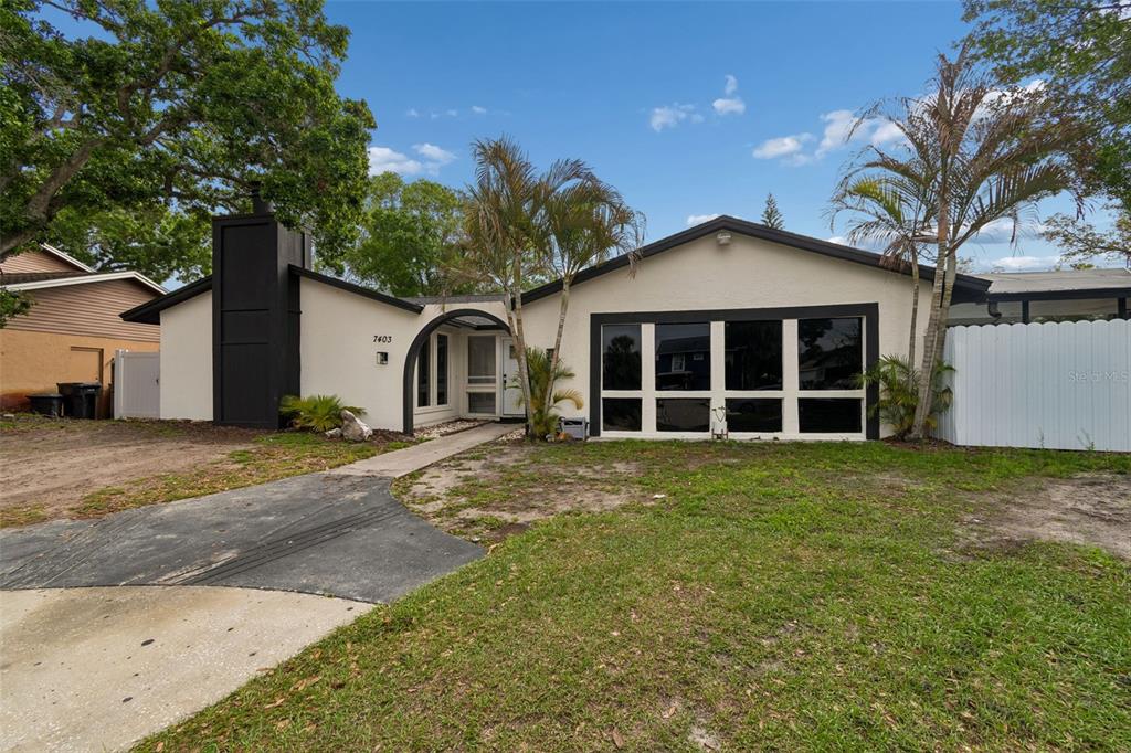 A single-story house with a black chimney, large windows, and a palm-lined front yard — 7403 SPRING COURT, TAMPA, FL