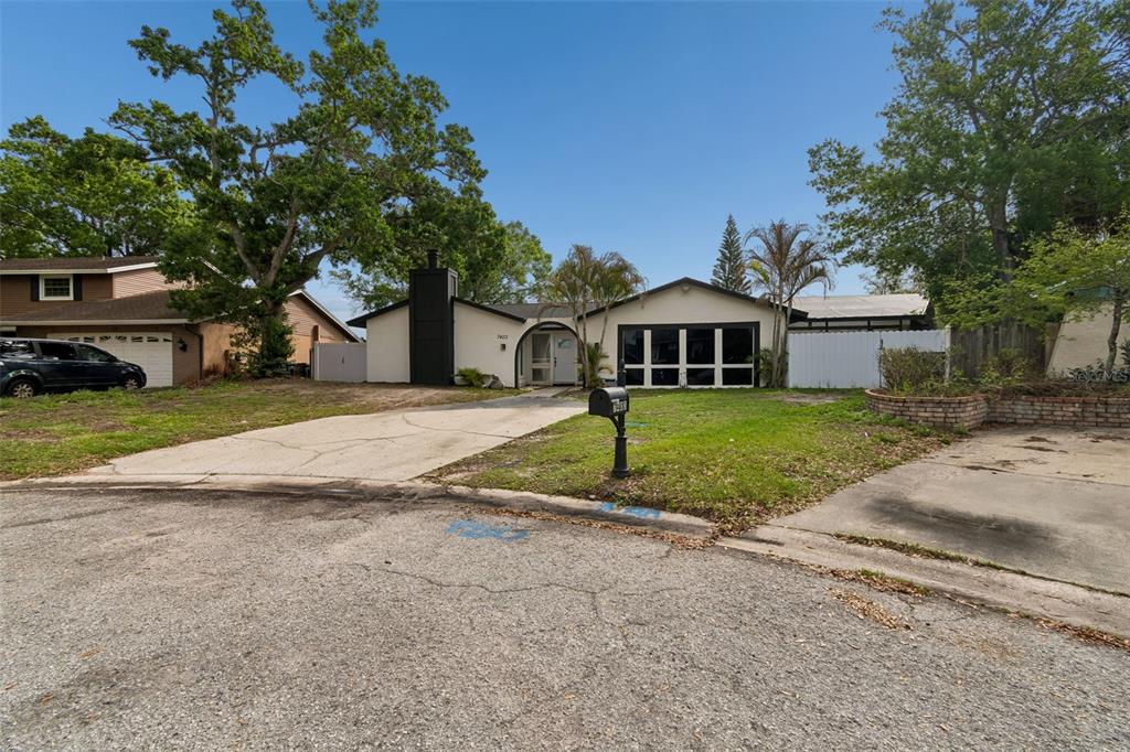 A single-story house with a white exterior, a black chimney, and a large front window — 7403 SPRING COURT, TAMPA, FL
