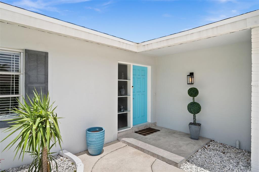 The exterior view shows a white house with a bright blue front door and entryway — 5122 SW 3RD AVENUE, CAPE CORAL, FL