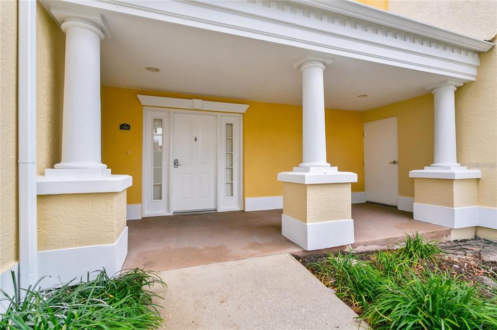 A covered porch with white columns leads to a white front door and side door — 1342 SEVEN EAGLES COURT, REUNION, FL