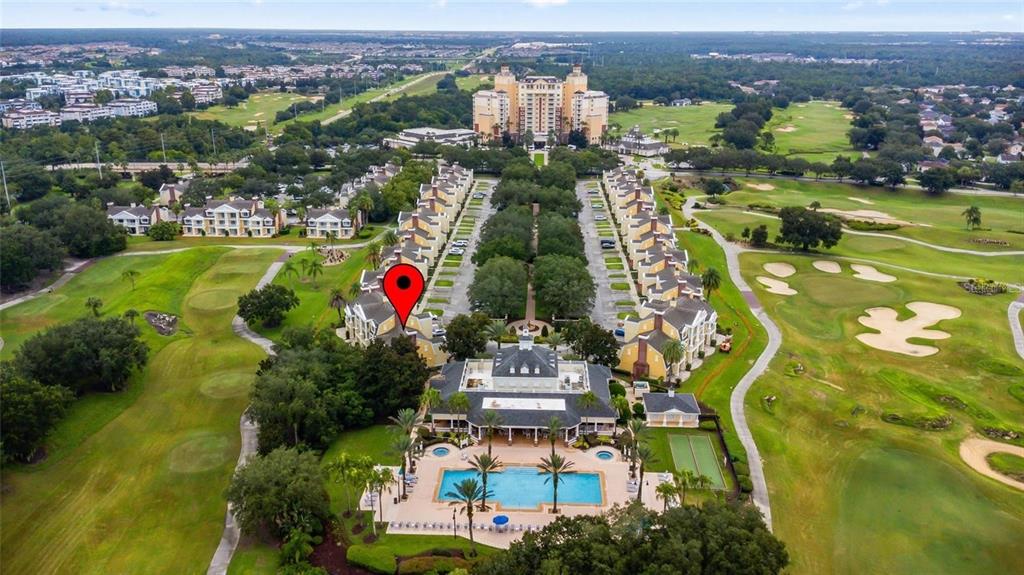 An aerial view shows a resort complex with a swimming pool, golf course, and buildings — 1342 SEVEN EAGLES COURT, REUNION, FL