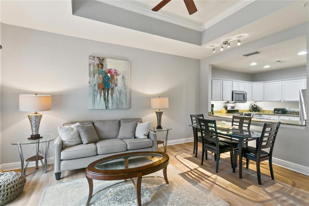 A living room with a gray sofa and dining area adjacent to an open kitchen — 1342 SEVEN EAGLES COURT, REUNION, FL
