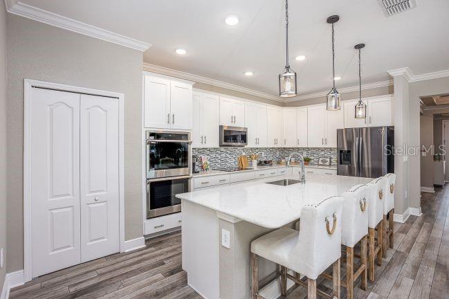 A modern kitchen features white cabinetry, a large marble-topped island, and stainless steel appliances — 21 SWEETBAY COURT E, HOMOSASSA, FL