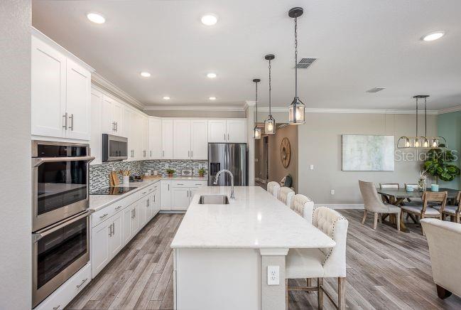 A modern kitchen features white cabinetry, a large quartz island, and stainless steel appliances — 21 SWEETBAY COURT E, HOMOSASSA, FL