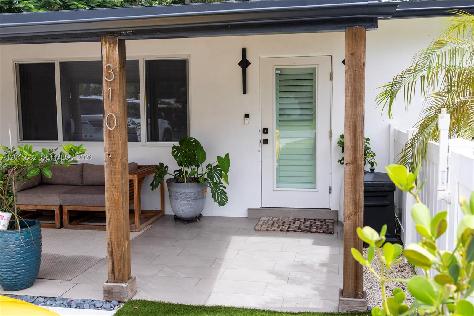 A covered patio features a white door, two wooden support posts, and potted plants — 310 NE 12th Ave, Pompano Beach FL 33060, POMPANO BEACH, FL