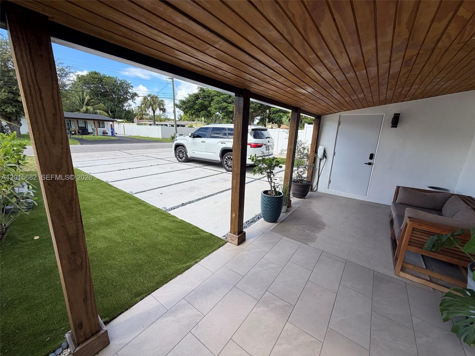 A covered patio features a tiled floor, wooden ceiling, and a view of a driveway — 310 NE 12th Ave, Pompano Beach FL 33060, POMPANO BEACH, FL