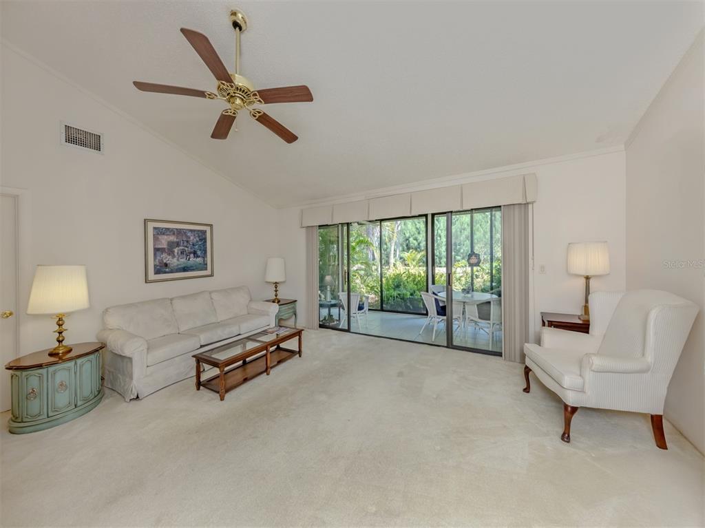 A living room features a white sofa, an armchair, a ceiling fan, and sliding glass doors — 868 BIRD BAY WAY UNIT 197, VENICE, FL